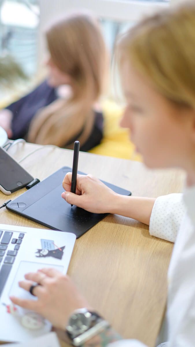 Vrouw gebruikt de trackpad van een laptop en tekent op een tekentablet