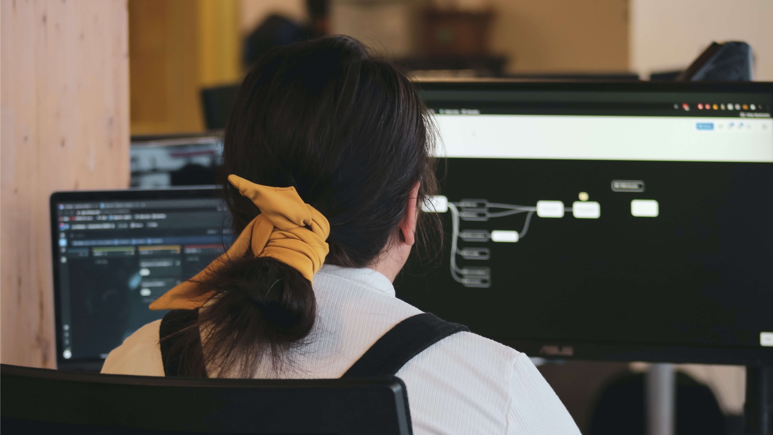 vrouw met een geel strikje rond haar paardenstaart maakt prototypes op haar computer